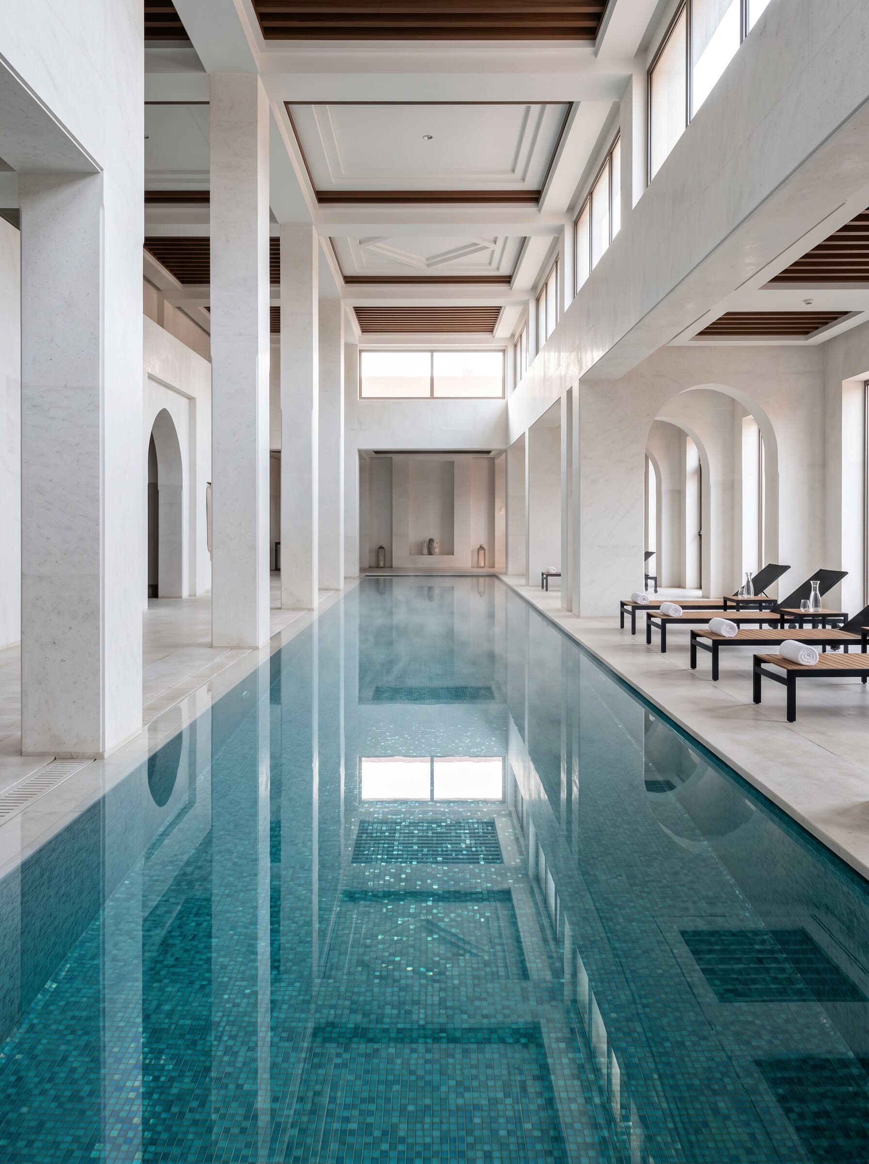 Piscine intérieure de 25 m en mosaïque bleu-vert, piliers de pierre blanche